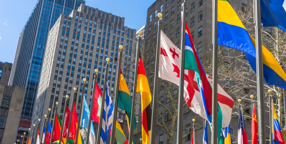 A row of international flags in a cityscape, symbolizing global diversity and the interconnected paths of the immigration journey.